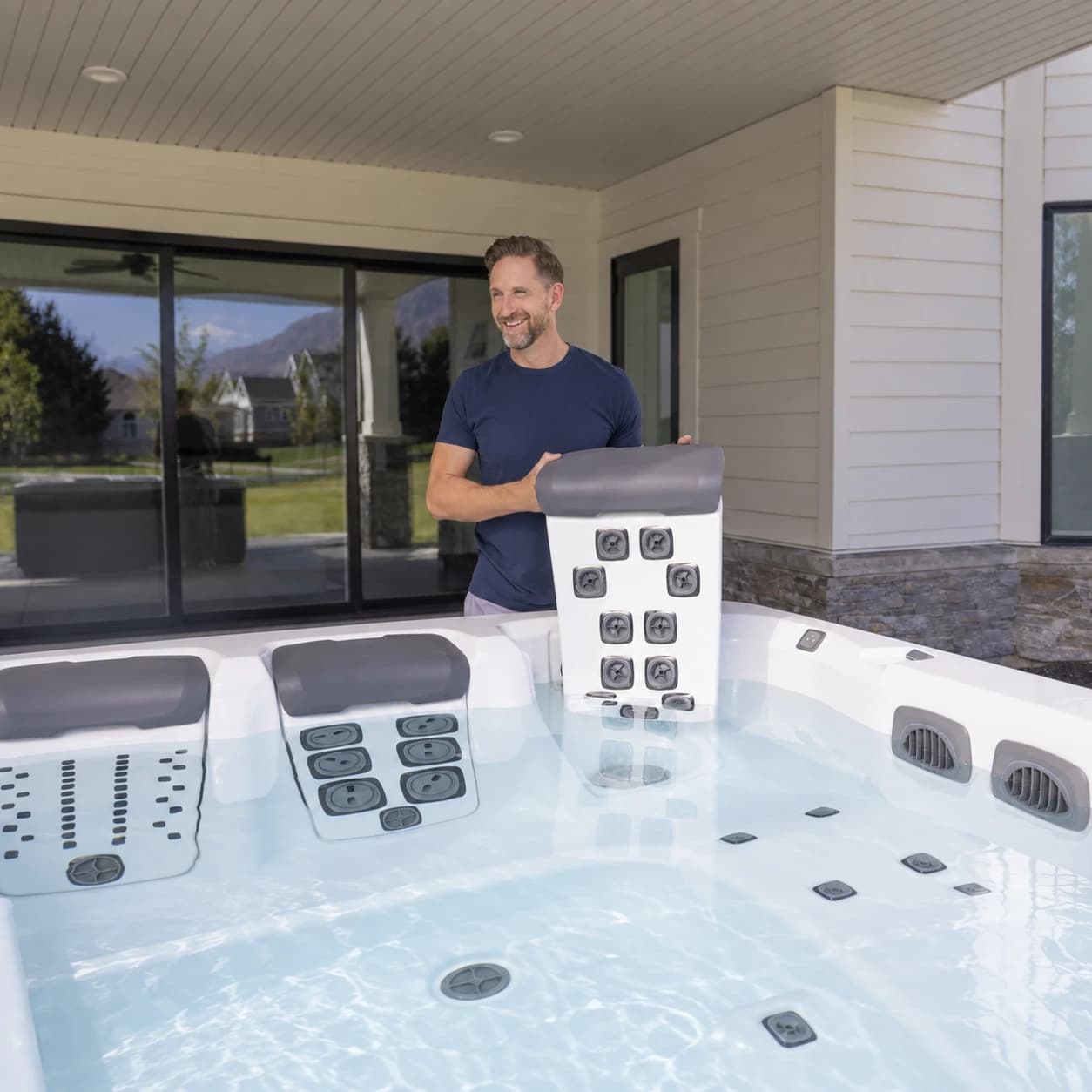 Bullfrog Spas A5D owner lifting a JetPak massage unit beside the filled hot tub