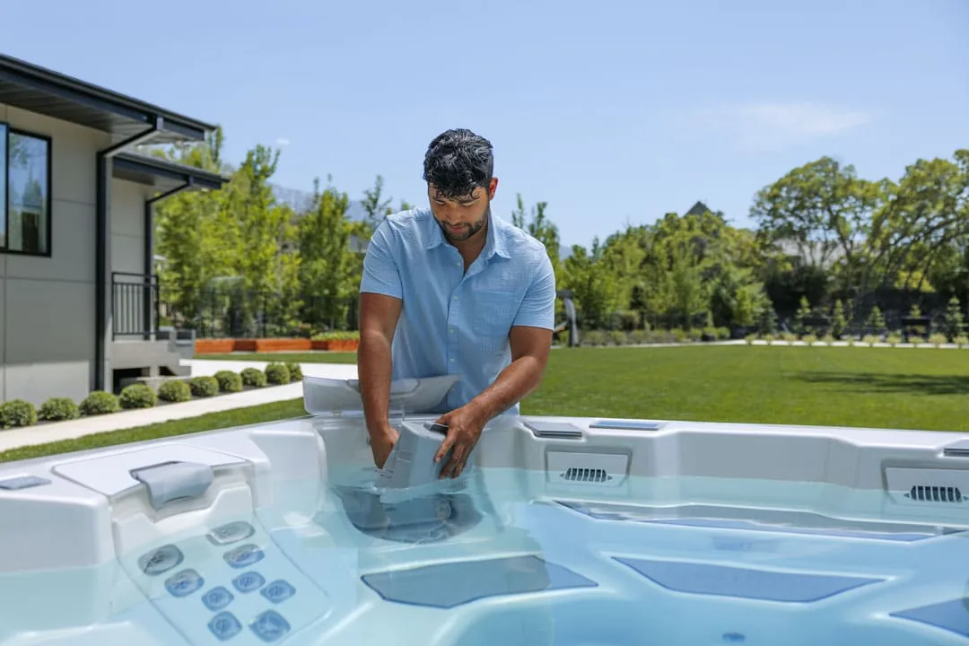Owner reaching into the filter compartment of a Bullfrog hot tub