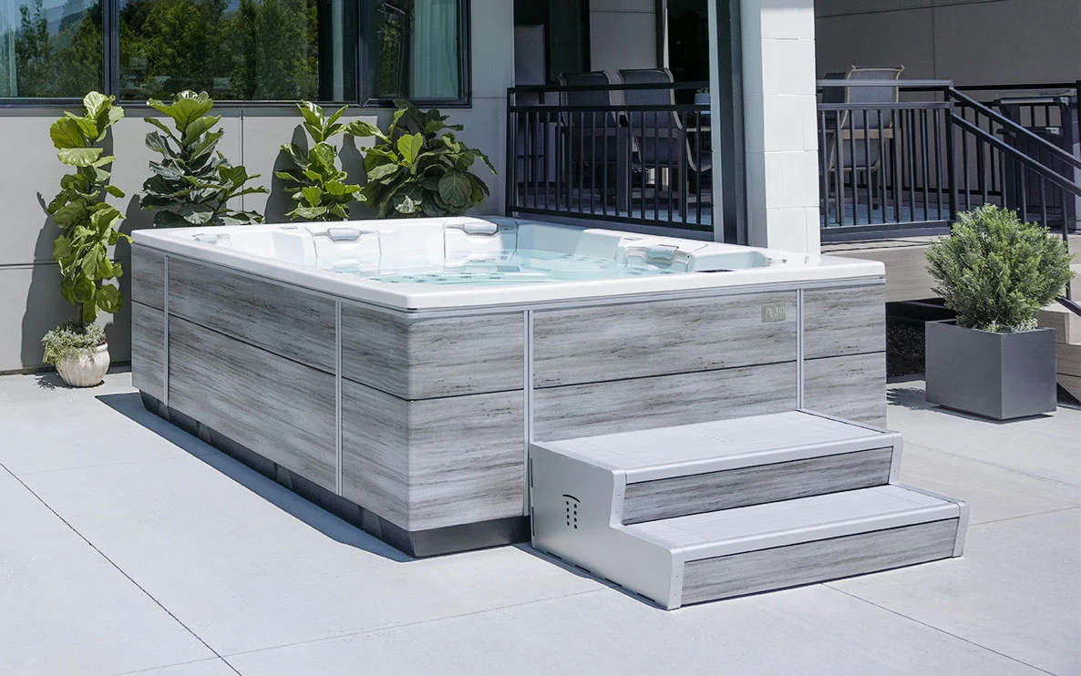 Bullfrog M Series hot tub on a bright patio with its complete cabinet, entry steps and seating visible