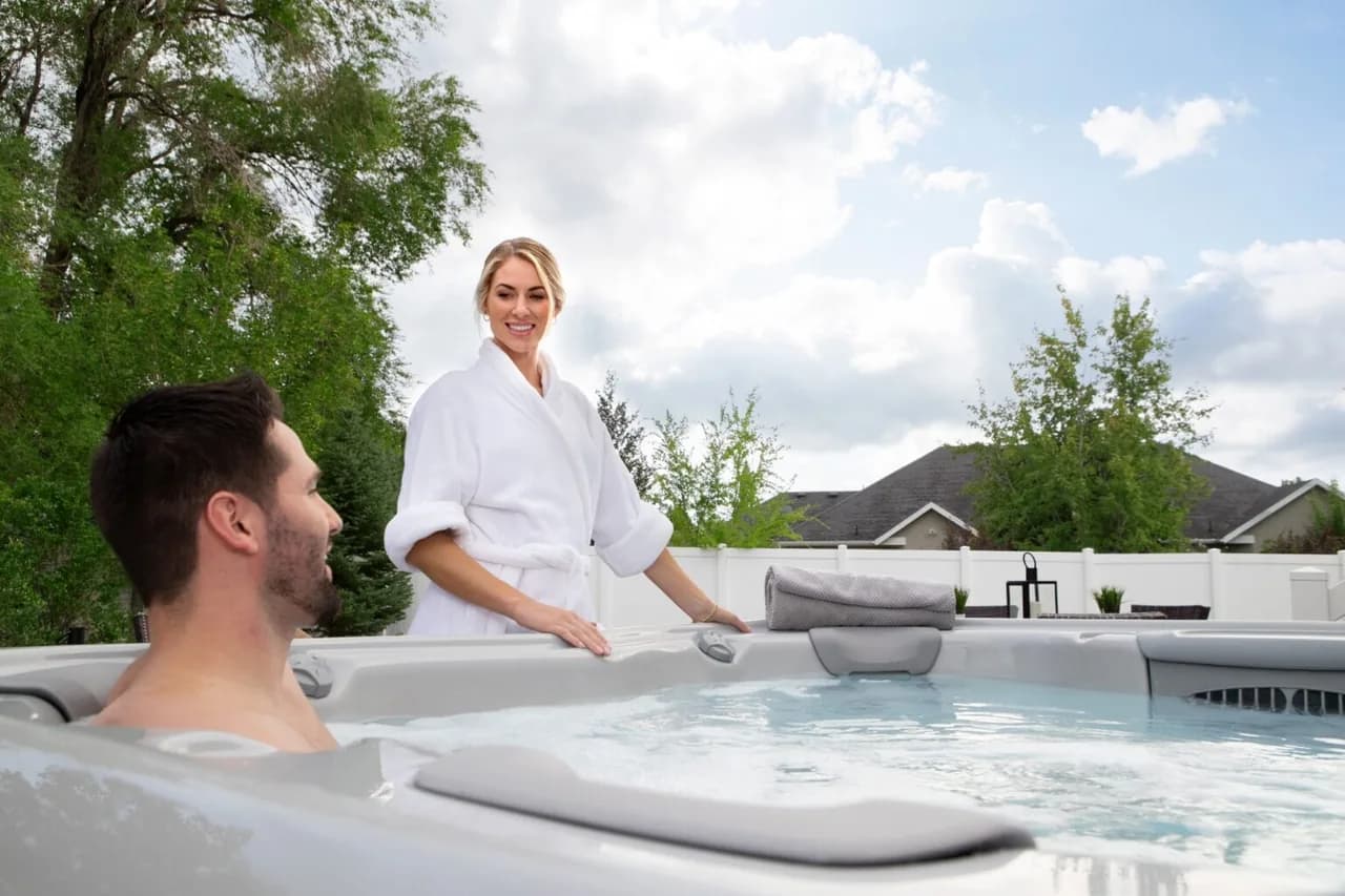 Two people enjoying a Bullfrog hot tub on a landscaped patio