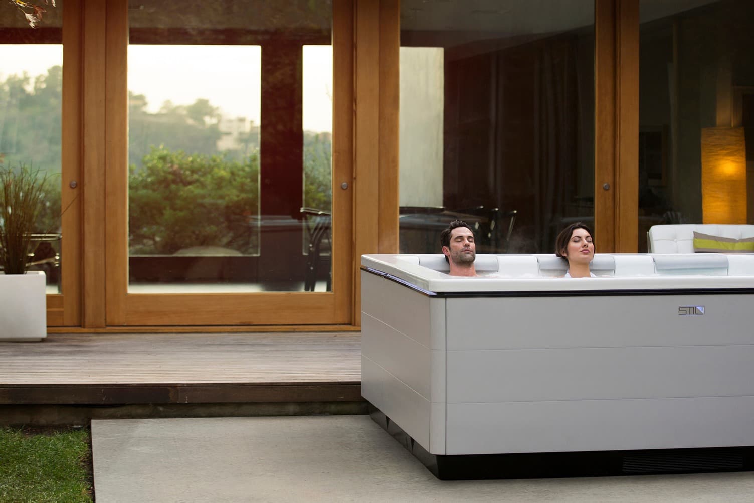 Two people in a white Bullfrog hot tub on a covered patio