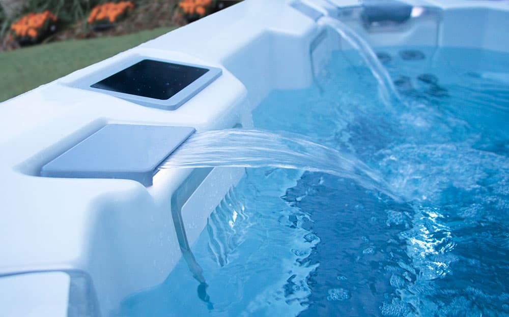 A clear waterfall pouring into the blue water of an M Series hot tub