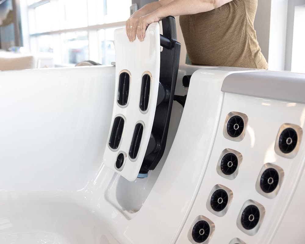 A hand lifting a removable JetPak seat back out of a Bullfrog spa