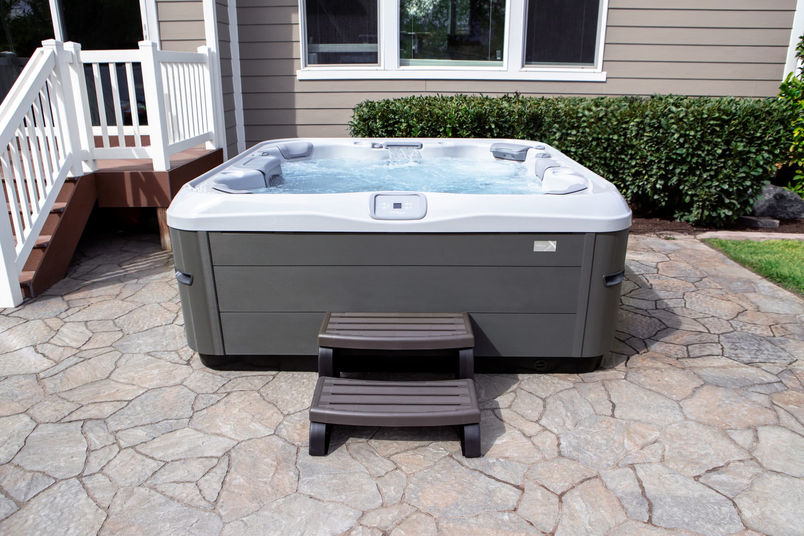 A Bullfrog X Series hot tub with steps on a stone patio
