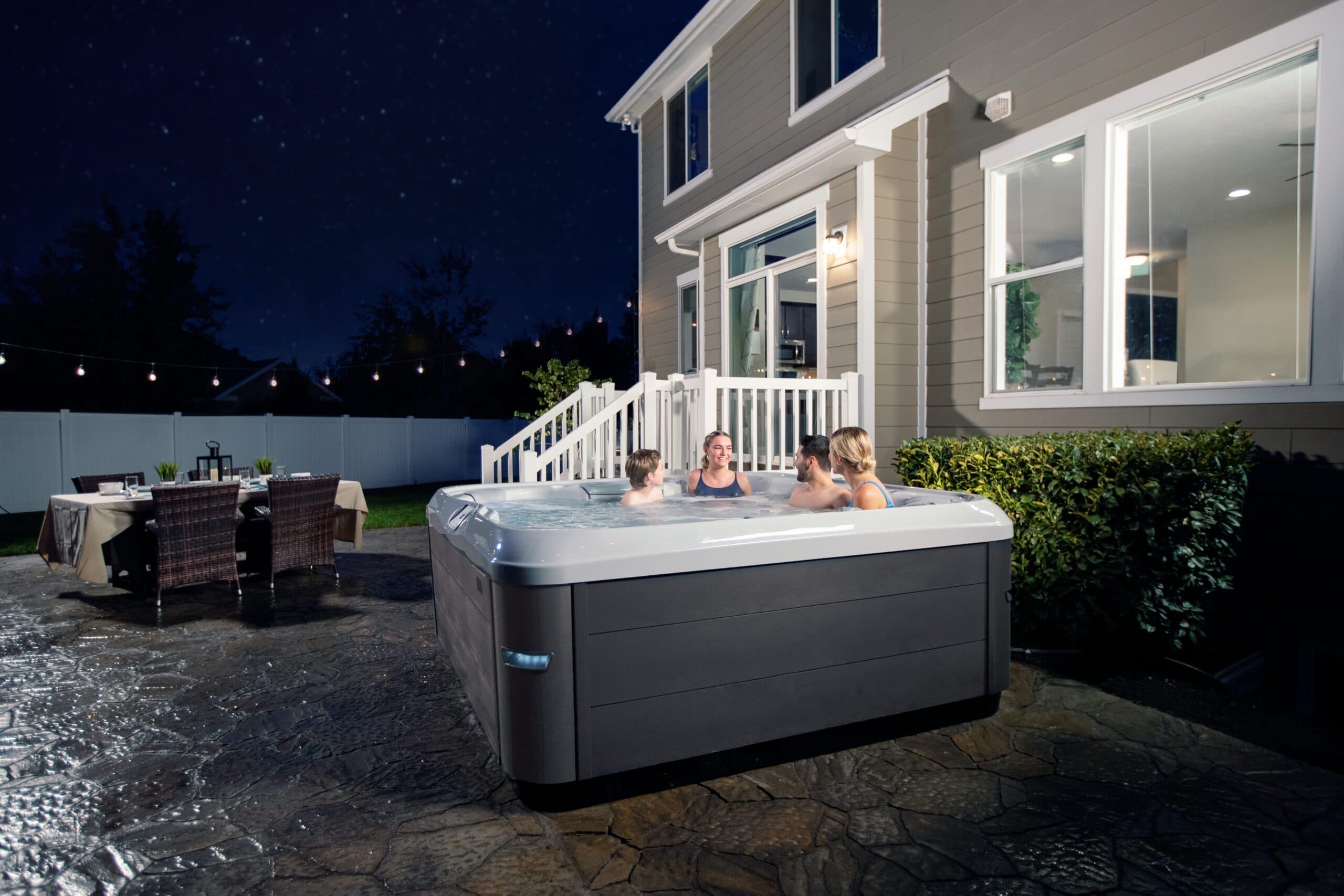 A family in a Bullfrog X Series hot tub on a patio at night