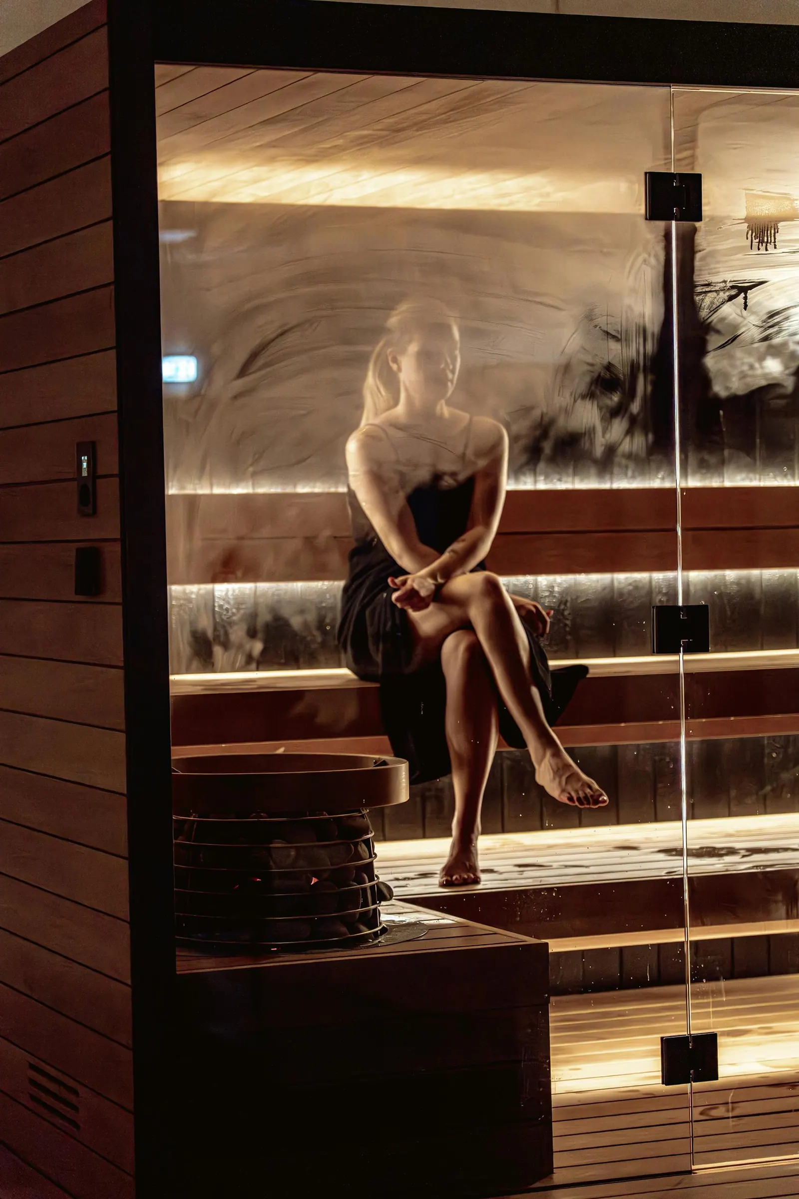 A woman sitting beside the heater stones inside a Hekla traditional sauna