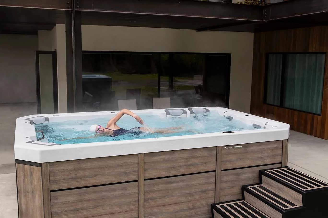 Person swimming in a Bullfrog Swim Series swim spa on an outdoor patio