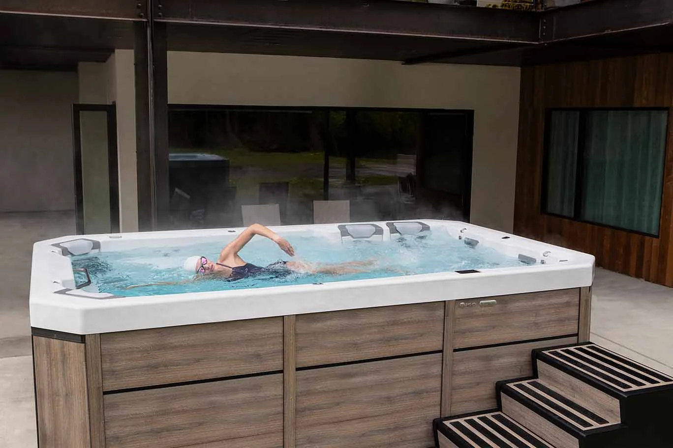 Bullfrog Spas swim spa beside a home with its cover open